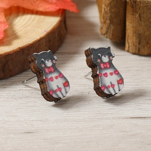 Pendientes de madera con forma de gato y lazo rojo sobre superficie de madera natural