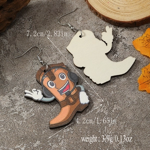 Detail of wooden cow-print boot earrings with measurements on a stone surface
