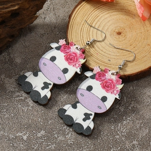 Detail of handmade wooden cow earrings featuring red floral crown and silver hooks