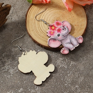Detailed view of pink elephant wooden earrings on natural wood base and stone background