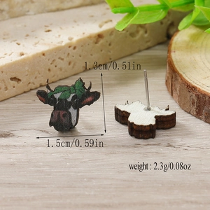 Vista macro di orecchini a lobo a forma di mucca in legno con dettagli di dimensioni