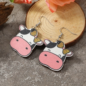 Detailed view of handmade cartoon cow earrings with pink glitter bows and silver hooks