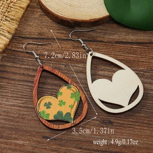 Detalle de pendientes de madera en forma de gota con corazón calado y patrón de trébol