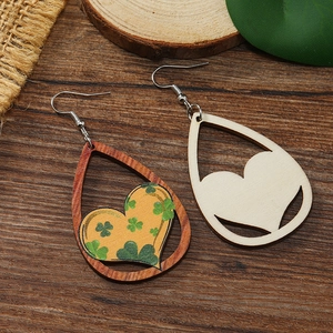 Detalle de pendientes de madera con forma de gota, trébol verde y diseño de corazón