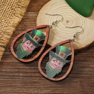 Close-up of St. Patrick's Day wooden teardrop earrings with leprechaun design on rustic wood
