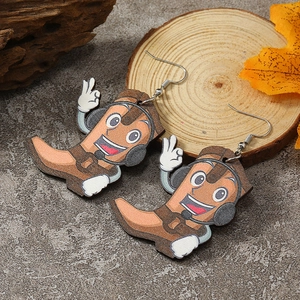 Close-up of cartoon boot character earrings on rustic wooden background with autumn leaves