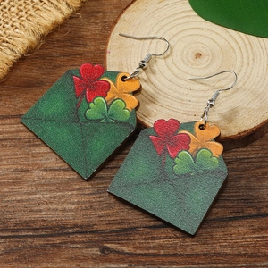 Detalle de pendientes de madera con forma de sobre verde y motivos de trébol de San Patricio