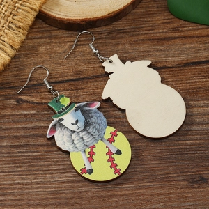 Detail view of St. Patrick's Day cartoon sheep earrings on wooden background
