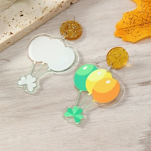 Detail of St. Patrick's Day acrylic earrings with shamrock charms on wood texture background