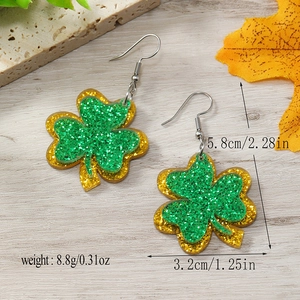 Vista macro de pendientes de trébol verde con purpurina y medidas 5,8 cm por 3,2 cm
