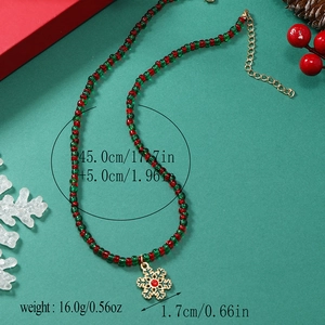 Detail van de kerstkralenketting met rood-groene kralen en gouden sneeuwvlok hanger