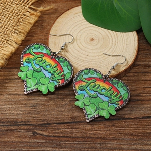 Detalle de pendientes de madera en forma de corazón con texto Lucky y diseño de tréboles
