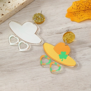 Detail of St. Patrick's Day acrylic earrings with sun hat and clover design on wood