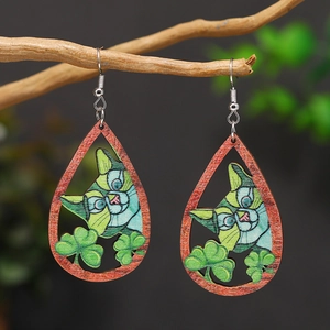Macro detail of teardrop wooden earrings featuring green cat and clover pop art patterns