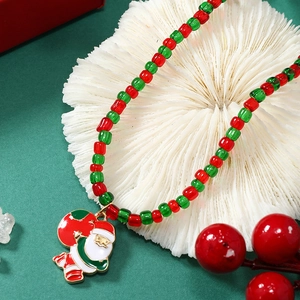 Chique kerstketting met rode en groene kralen en kerstman hanger op wit koraal plateau