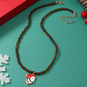 Detail van kerstketting met rood groene kralen en prachtige kerstman hanger goud