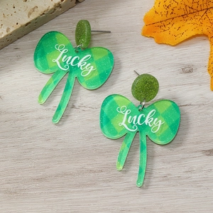 Primer plano de pendientes de lazo acrílico a cuadros verdes con texto Lucky en blanco