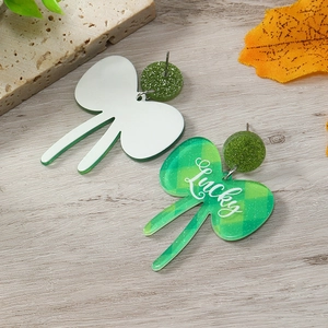 Detalle de pendientes de trébol para San Patricio con texto Lucky sobre fondo madera