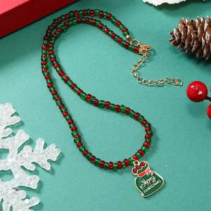 Detail van kerstketting met rode en groene kralen en geëmailleerde kersttasje hangertje