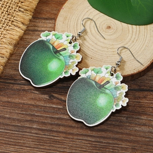 Vista detallada de pendientes de madera con forma de manzana verde sobre un fondo rústico
