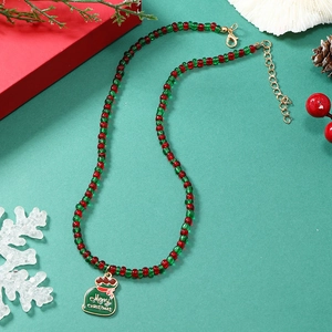 Detail van kerstparelketting met groene geschenkhanger en rode en groene ronde kralen