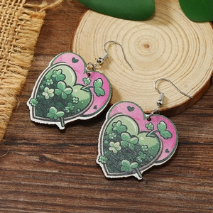Dettaglio degli orecchini in legno a forma di cuore rosa e verdi con motivi a trifoglio