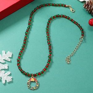 Detail van kerstketting met rood-groene kralen en een feestelijke kransvormige hanger