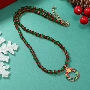 Close-up van een kerstkrans hanger aan een rood-groene kralenketting met decoratieve props