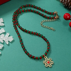 Detail van deze kerstketting met rode en groene kralen en een sneeuwvlok hanger