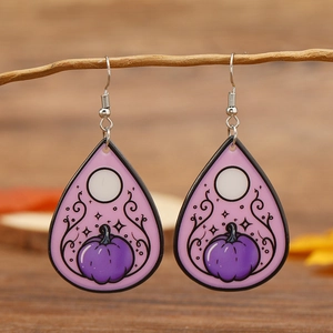 Close-up of teardrop acrylic earrings with pumpkin illustration on autumn branch