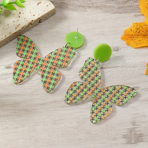 Vista detallada de pendientes de mariposa de acrílico con cuadros verdes y naranjas