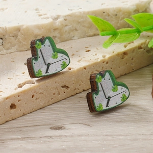 Dettaglio di orecchini a lobo in legno a cuore con stampa quadrante e quadrifoglio verde