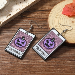 Detail of tarot card acrylic earrings with purple pumpkin design and autumn decorations