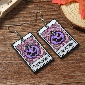 Detail of purple acrylic Jack-o-lantern earrings on wooden background with autumn leaves