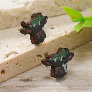 Dettaglio di orecchini a lobo testa di toro in legno con fiocco verde e grana del legno