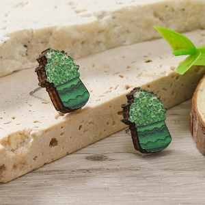 Dettaglio di orecchini in legno a quadrifoglio con trama di foglie verdi su pietra naturale