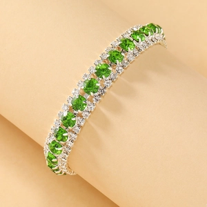 Elegante groene kristallen armband met drie rijen stenen op een strakke beige achtergrond