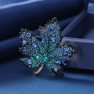 Detalle macro de broche de hoja de arce de cristal con pedrería azul en degradado