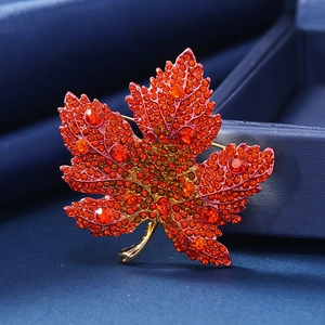 Broche lujoso de hoja de membrillo con cristales naranjas y diamantes rojos sobre oro