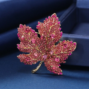 Luxuriöse goldene Ahornblatt-Brosche mit rosa Kristallen auf dunkelblauem Samt