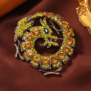 Detail of vintage bronze dragon brooch with yellow-green rhinestones and amber crystals