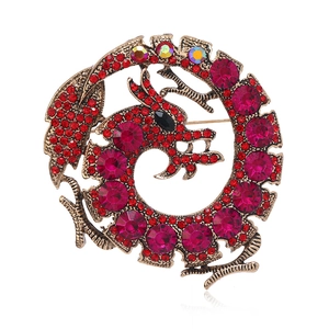 Detailed view of vintage dragon brooch with red crystals and antique gold finish