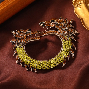 Vintage bronze dragon brooch with yellow and orange rhinestones on silk background