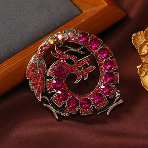 Vintage gold dragon brooch with red crystals on satin background for suits