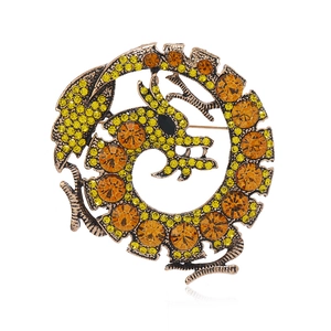 Vintage gold dragon brooch featuring sparkling yellow and orange rhinestones on white background
