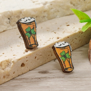 Vista macro di orecchini a perno in legno per San Patrizio con boccale di birra e trifoglio