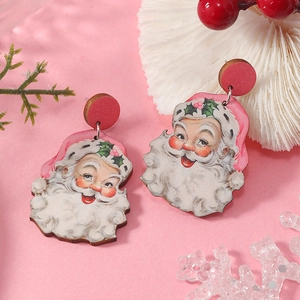 Festive Christmas tree earrings featuring Santa Claus pendants on warm pink background