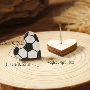 Close-up of heart-shaped football pattern wooden earrings on natural wood slice