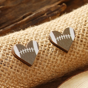 Close-up of heart-shaped wooden stud earrings featuring an American football print design