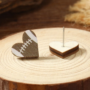 Macro shot of heart-shaped wooden football earrings with rugby stitching details